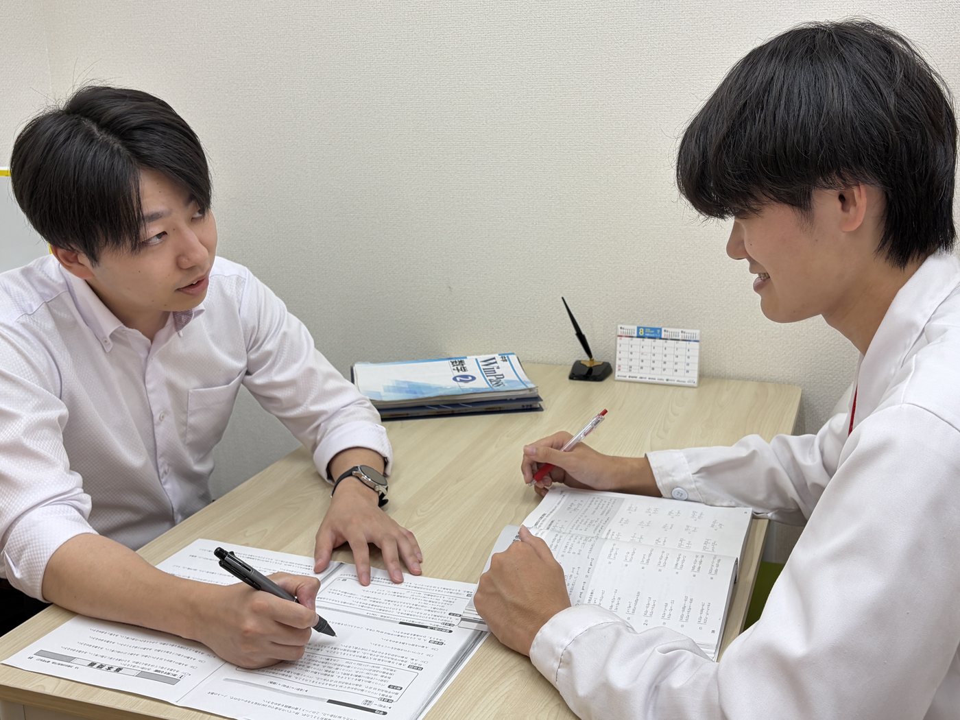 机を挟んで資料を見ながら話し合う様子